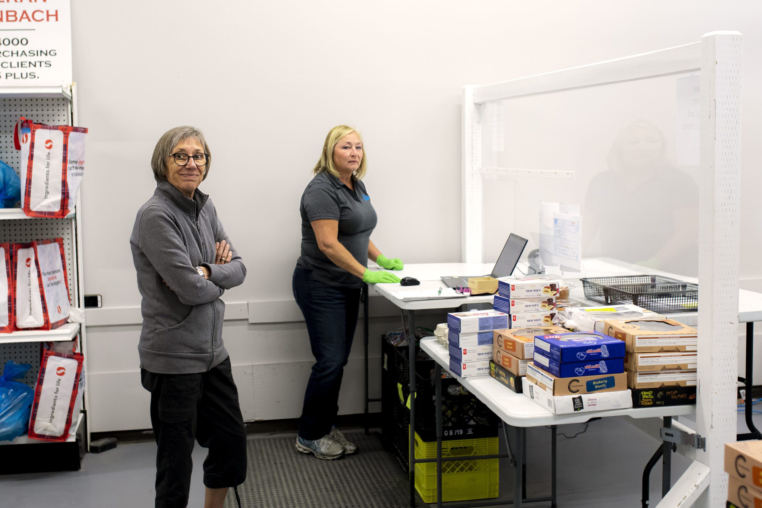 June7,20238708 man holding a box of food with people sorting food behind him